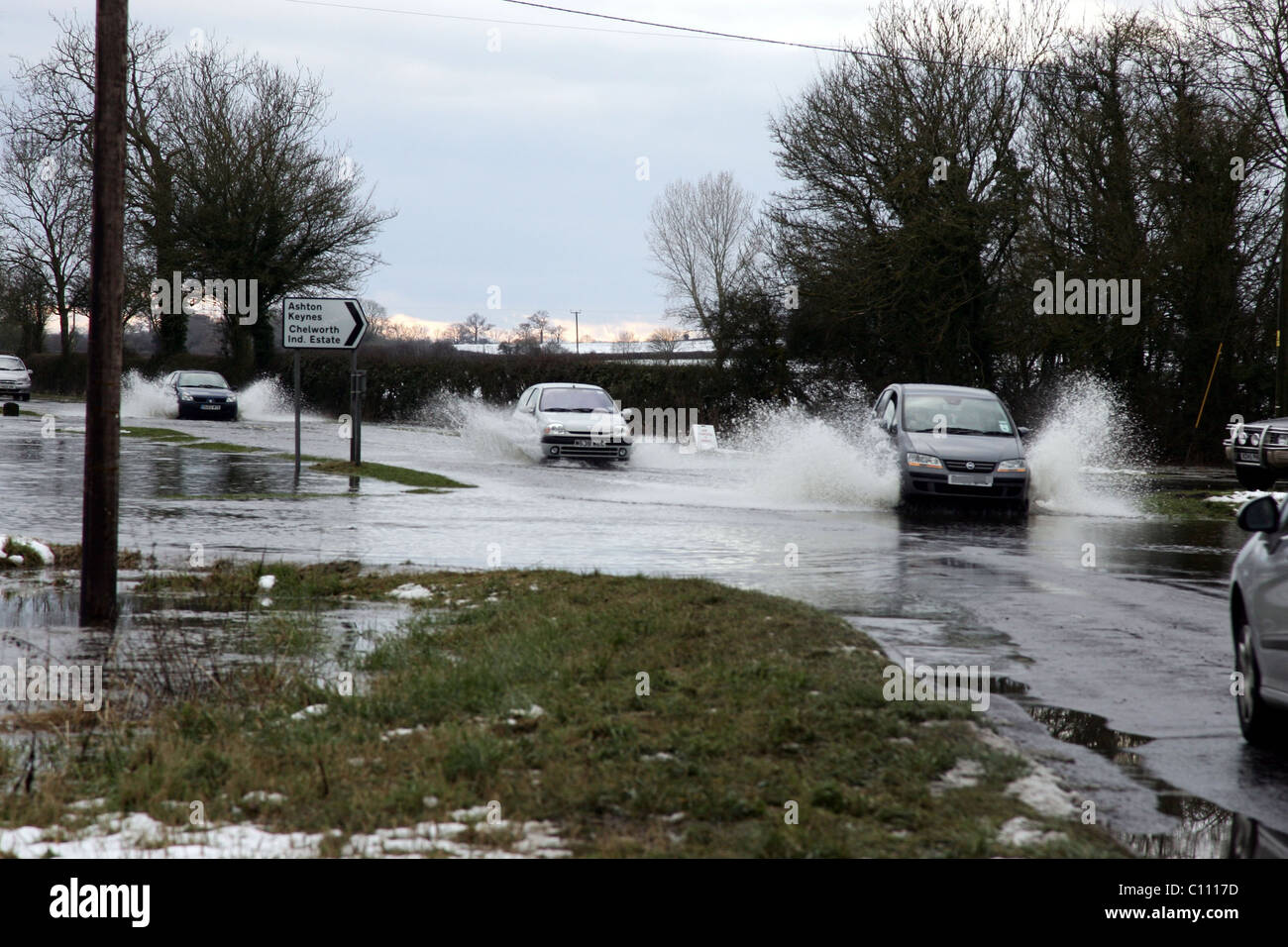 Motorists pass through floods caused by melting snow and ice on the