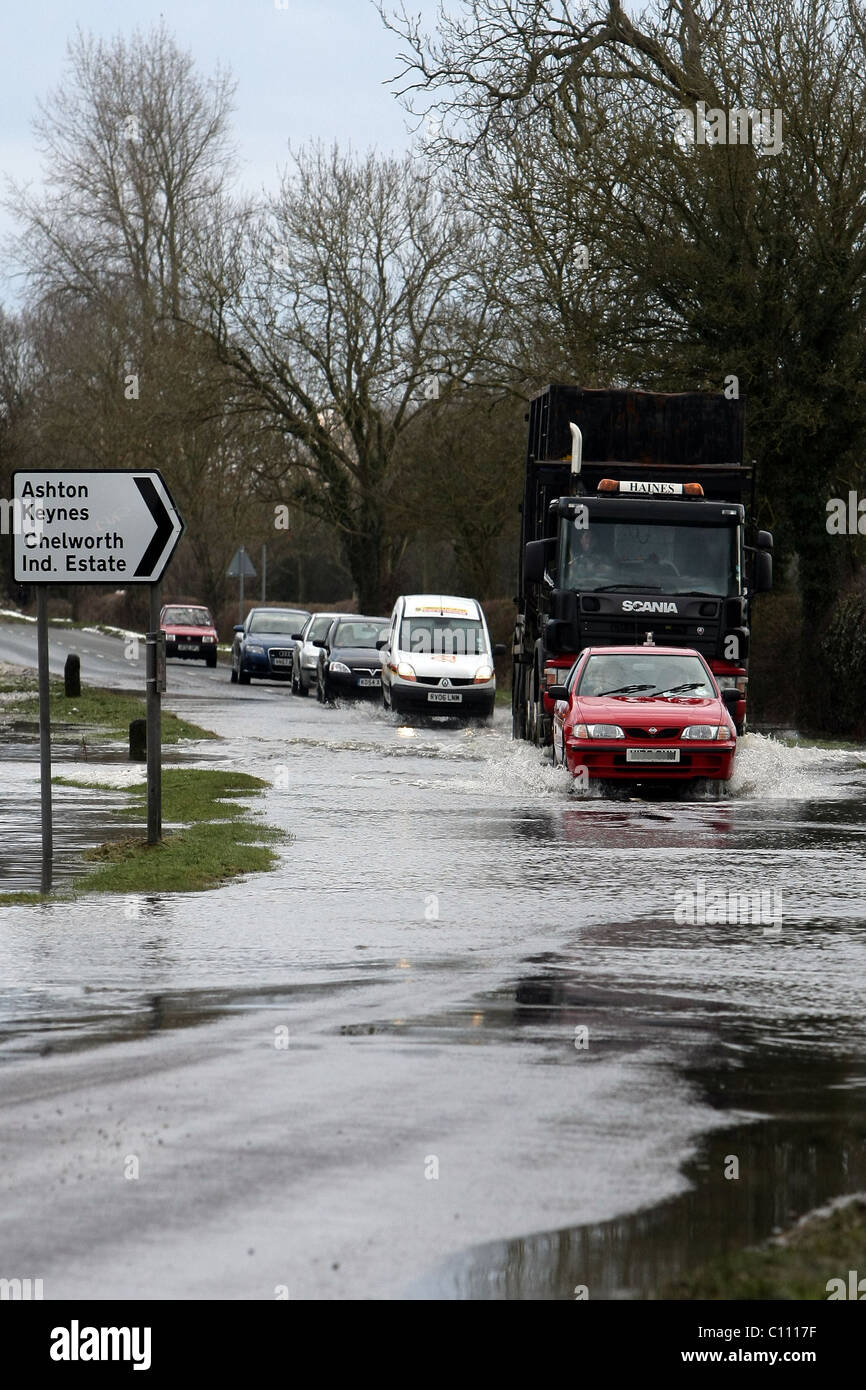 Motorists pass through floods caused by melting snow and ice on the