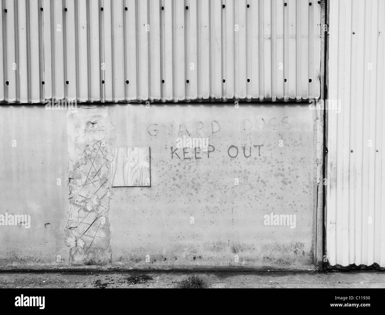 'Guard Dogs Keep Out' sign on side of farm shed building Stock Photo