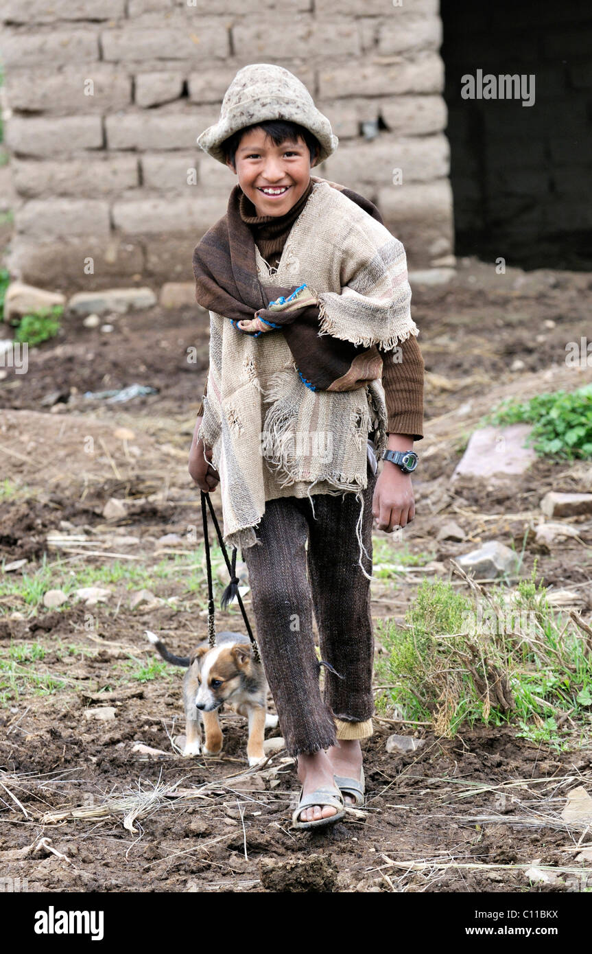 Shepherd boy in traditional dress with puppy on a leash, Altiplano Bolivian highland, Oruro Department, Bolivia, South America Stock Photo