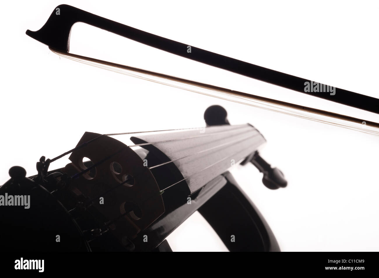 Violin bow above the strings of an electric violin on a white