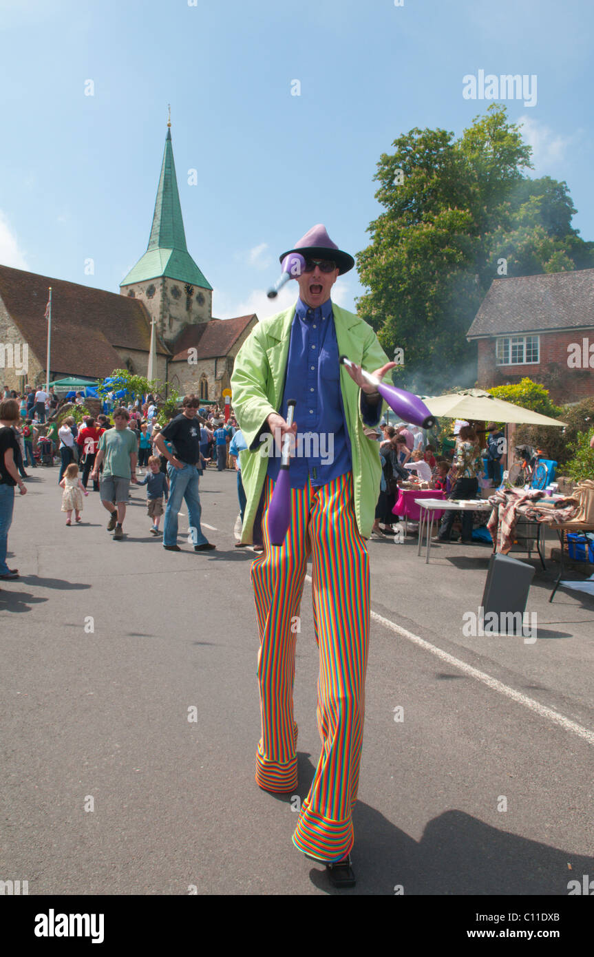 Tall man on stilts juggling at Harting Festivities. Fete held annually at May at South Harting, West Sussex, UK. Stock Photo