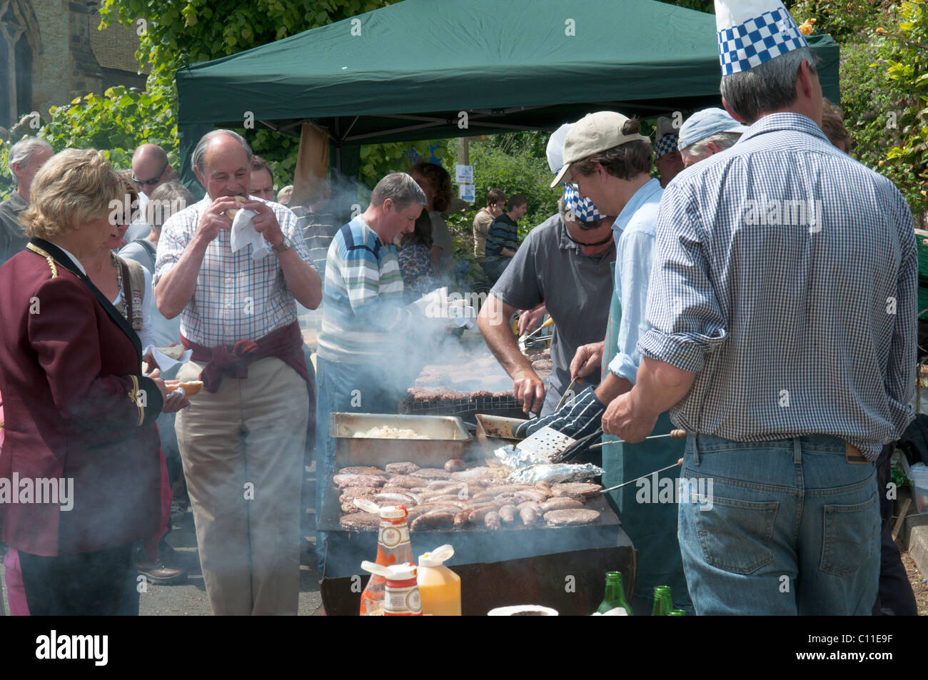 Cooking food ,burgers, sausages, outside on barbecue at  Harting Festivities. Fete held annually at May at South Harting, West Sussex, UK. Stock Photo