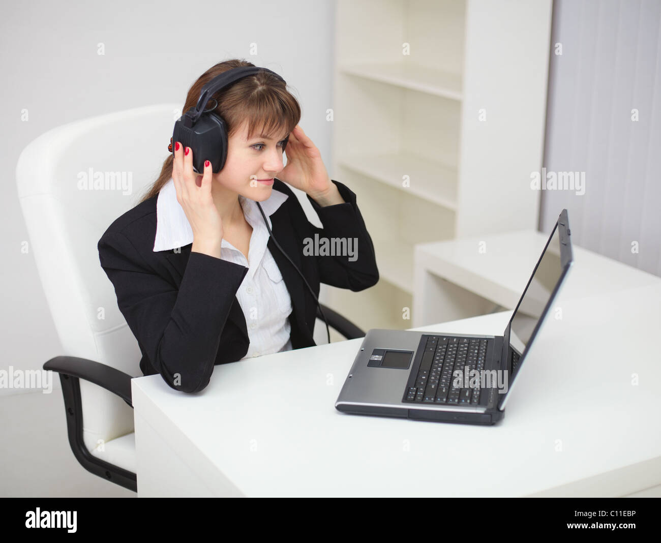 Woman listens to music by means of laptop and ear-phones Stock Photo