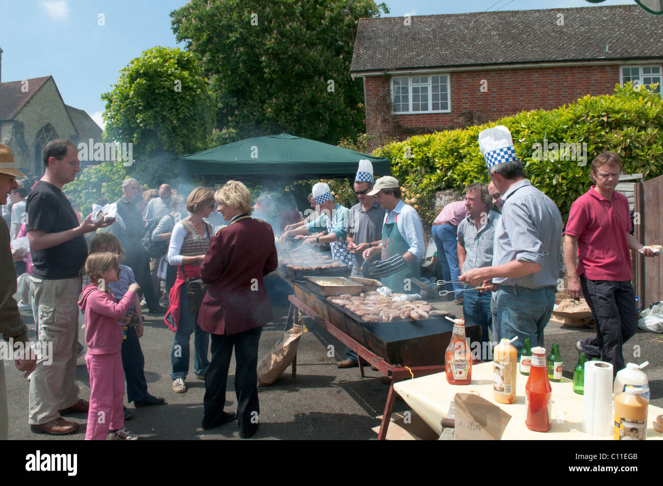 Cooking food ,burgers, sausages, outside on barbecue at  Harting Festivities. Fete held annually at May at South Harting, West Sussex, UK. Stock Photo