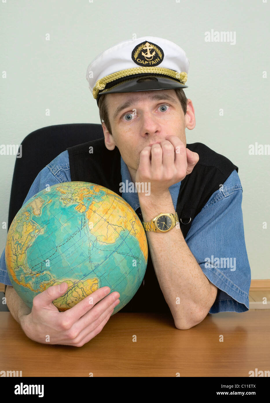 Seaman misses on distant travel sitting at table with globe Stock Photo
