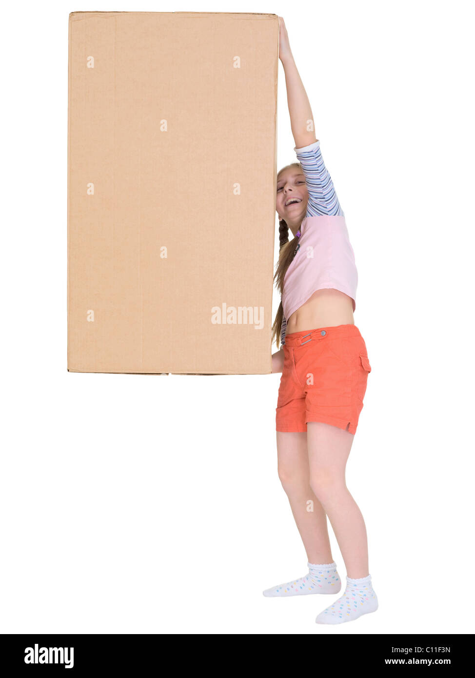 Small cheerful girl drags big cardboard box isolated on white Stock Photo