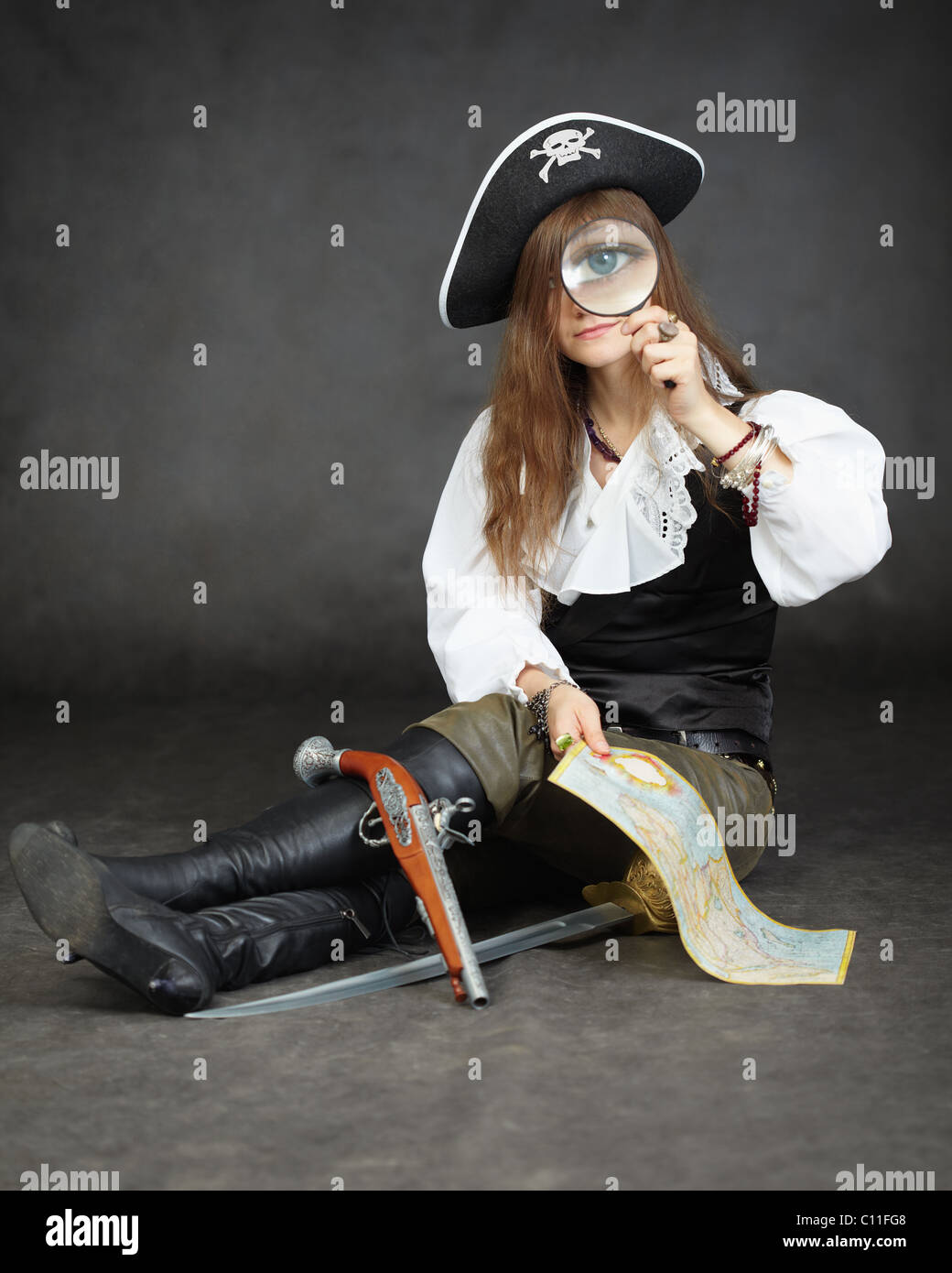 Girl pirate, and map with a magnifying glass on black background Stock Photo