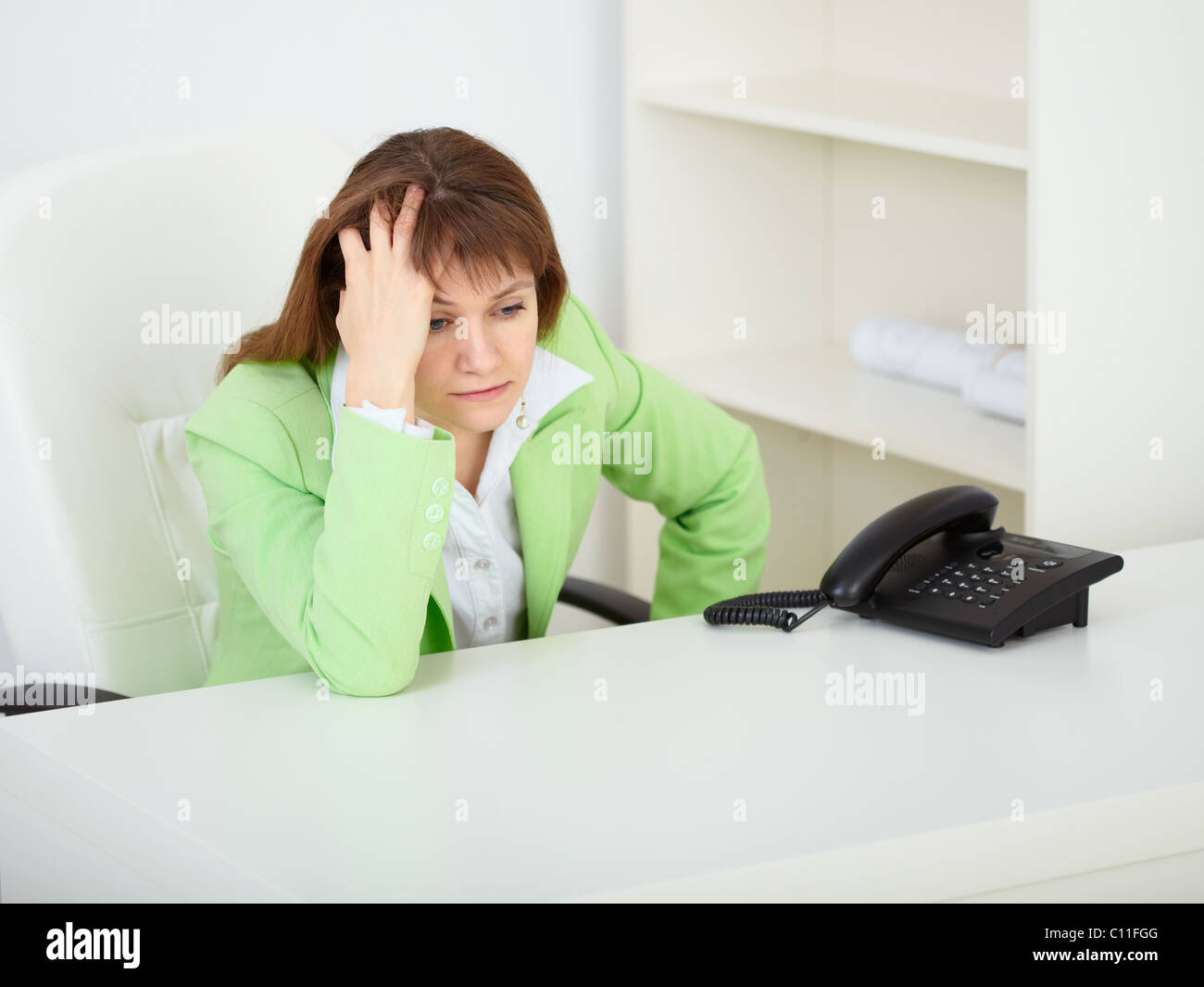 A sad young woman in office at workplace Stock Photo