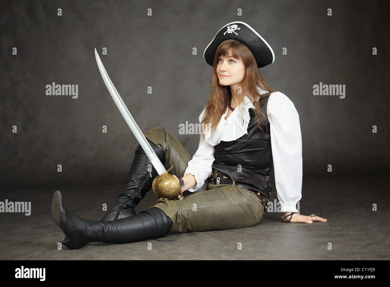 Woman - captain of pirates sitting on black background with a sabre Stock Photo