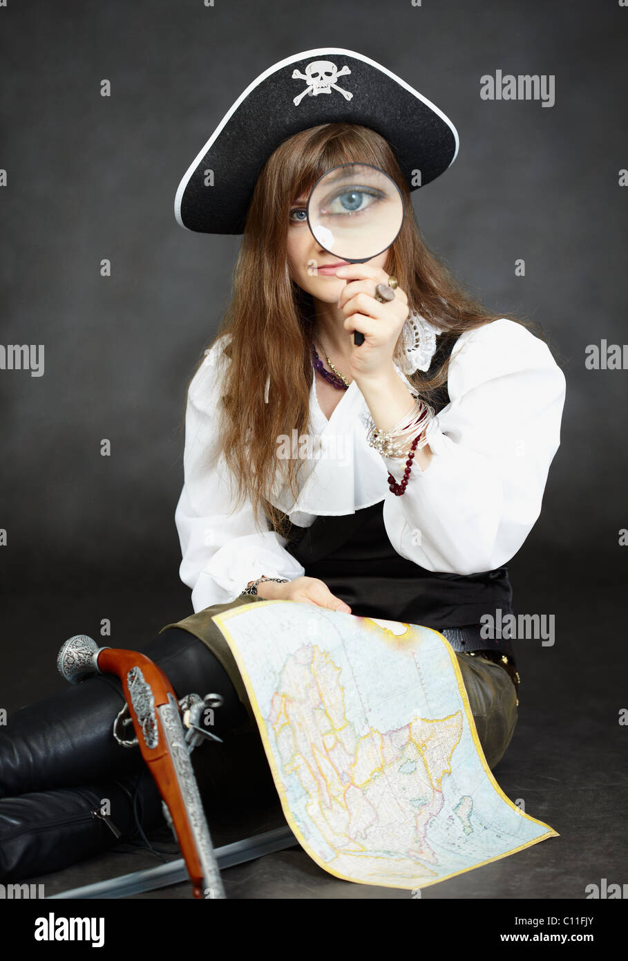 Woman pirate, and map with a magnifying glass on black background Stock Photo
