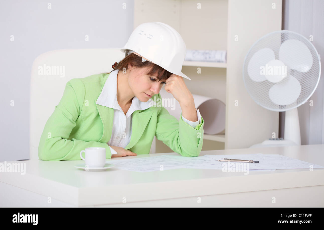 Tired woman engineer in workplace Stock Photo