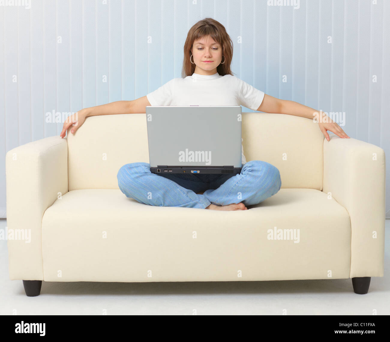 Beautiful girl looking movie sitting on couch with laptop Stock Photo