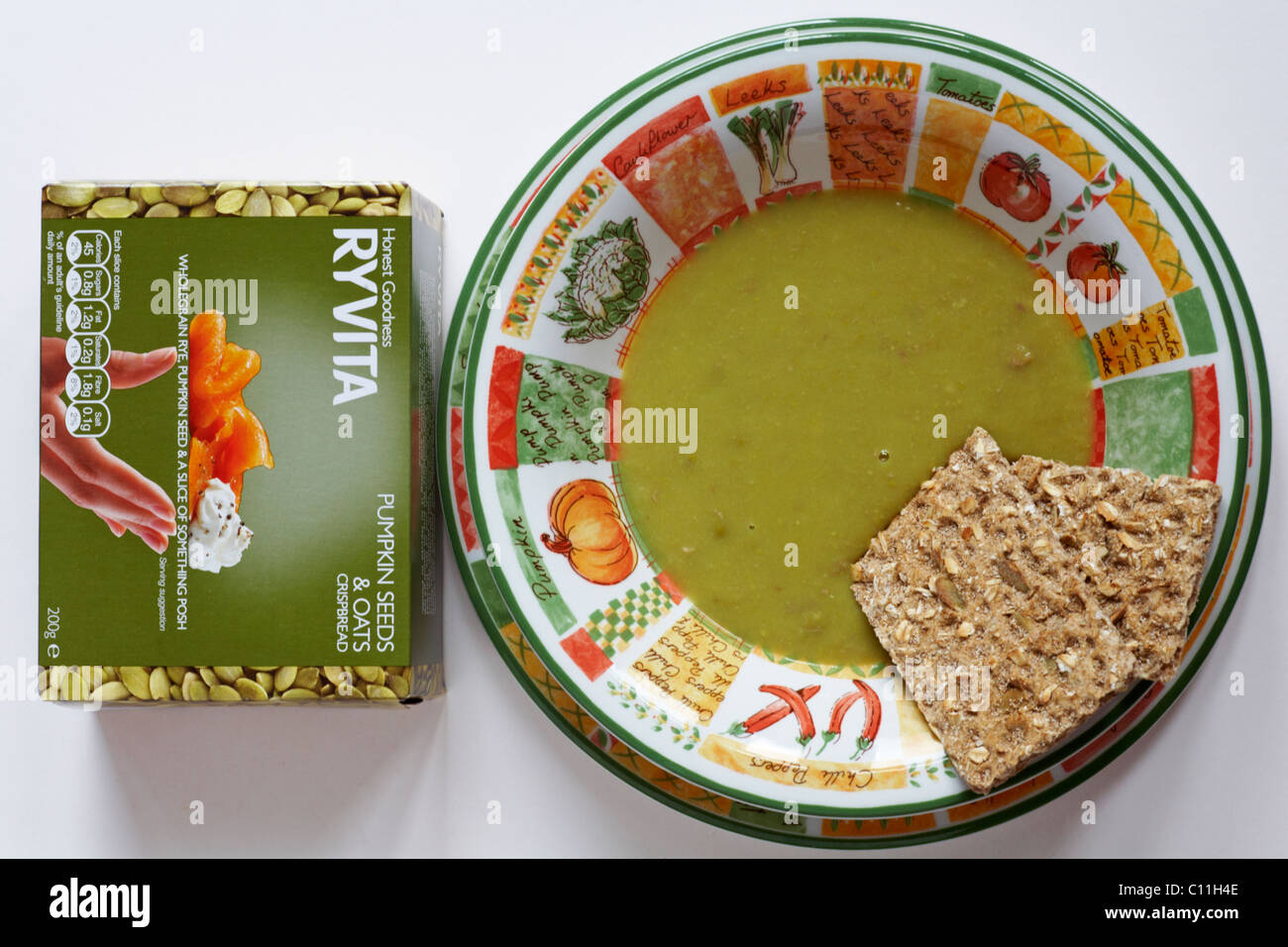 Bowl of pea and ham soup with packet of Ryvita pumpkin seeds and oats crispbread isolated on white background Stock Photo