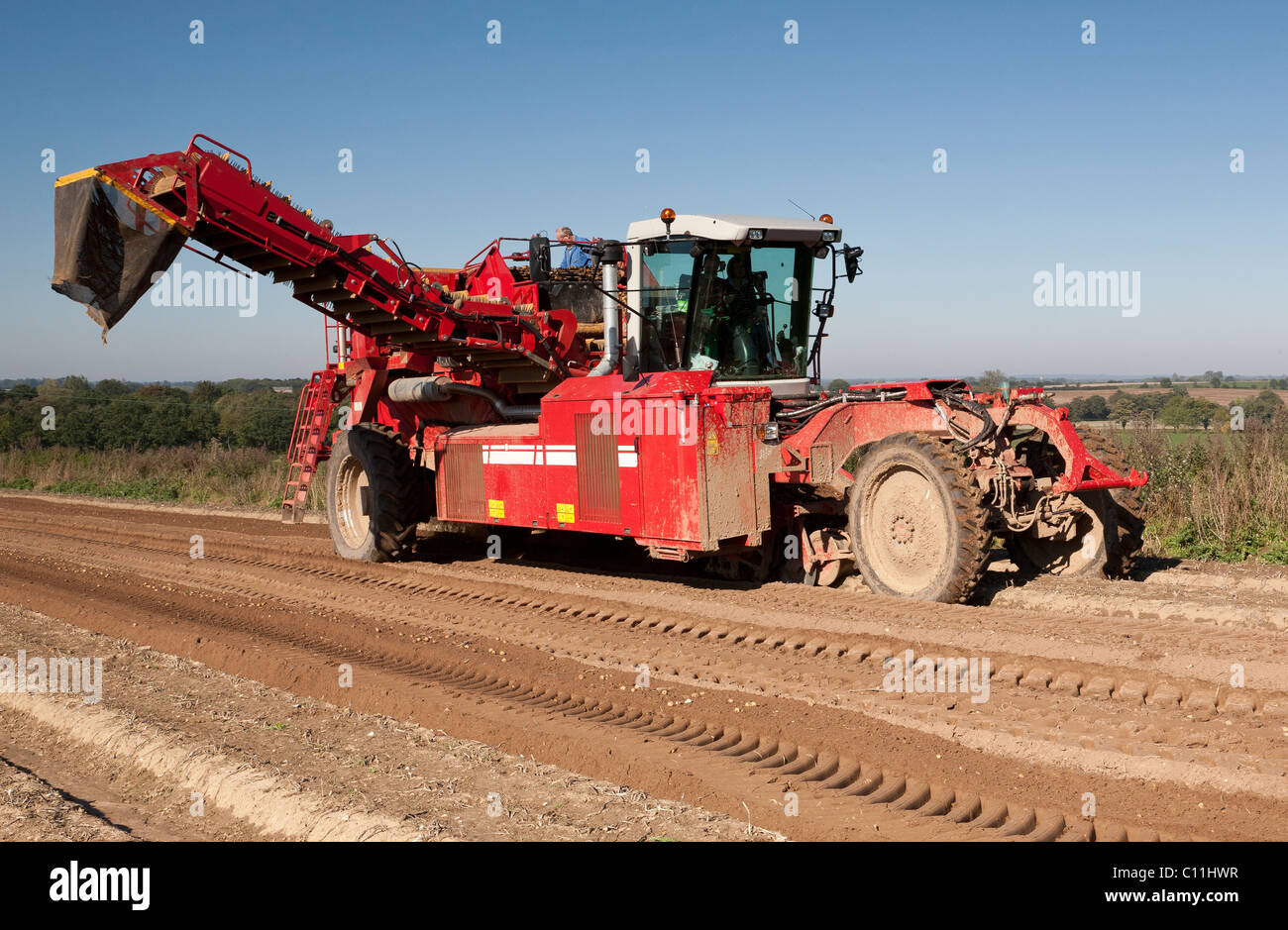A farmer driving a potato harvester ready to lift potatoes Stock Photo