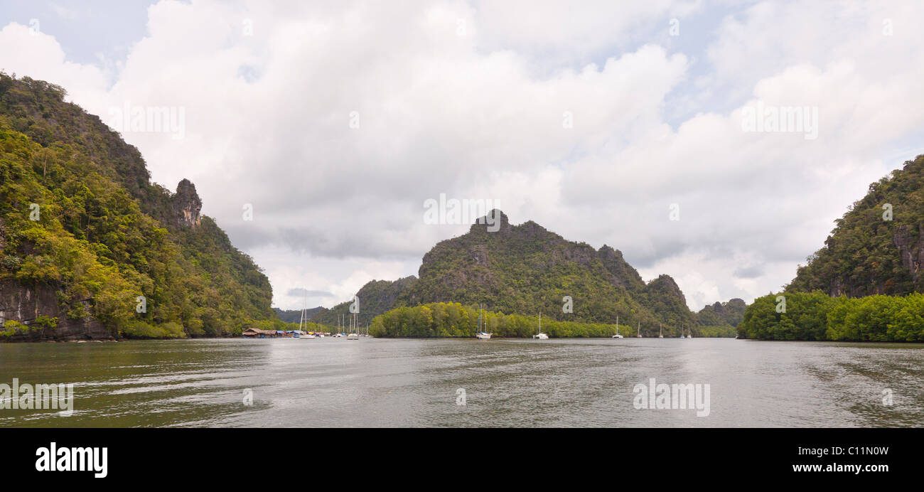 Pulau Langkawi GeoPark, Malaysia, forested hills amongst surrounding sea water, moored boats Stock Photo
