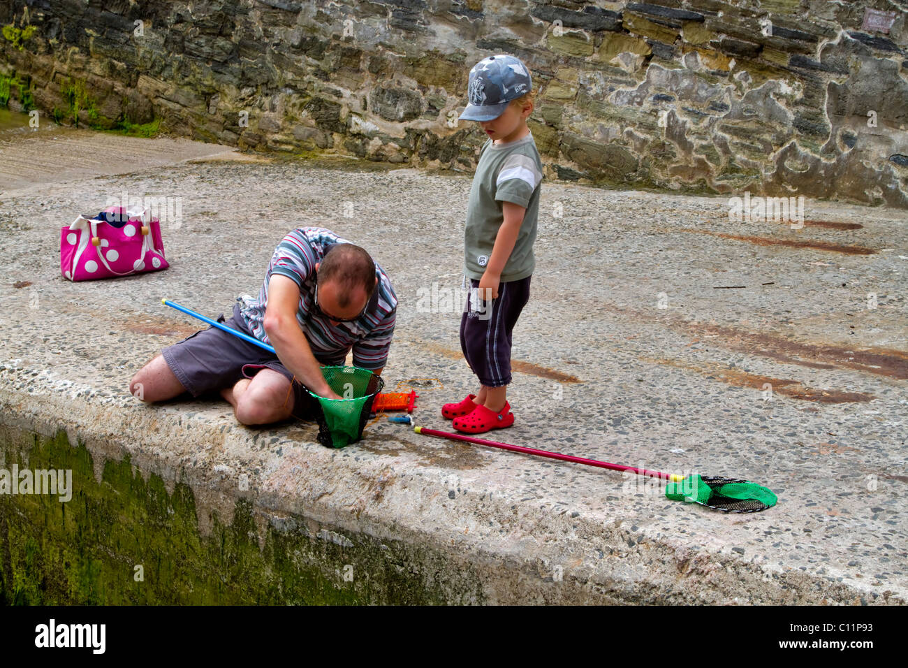 Father and son crabbing from a boat launch ramp in Salcombe, South Hams, Devon. Stock Photo