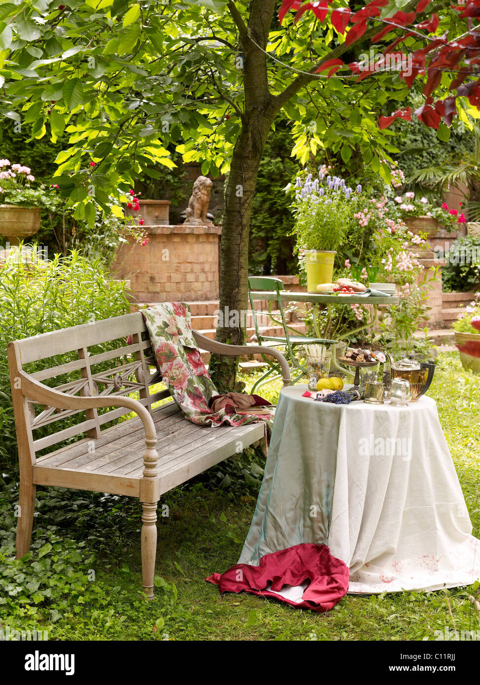 Old garden bench with a nicely laid table, romantic ambience Stock Photo