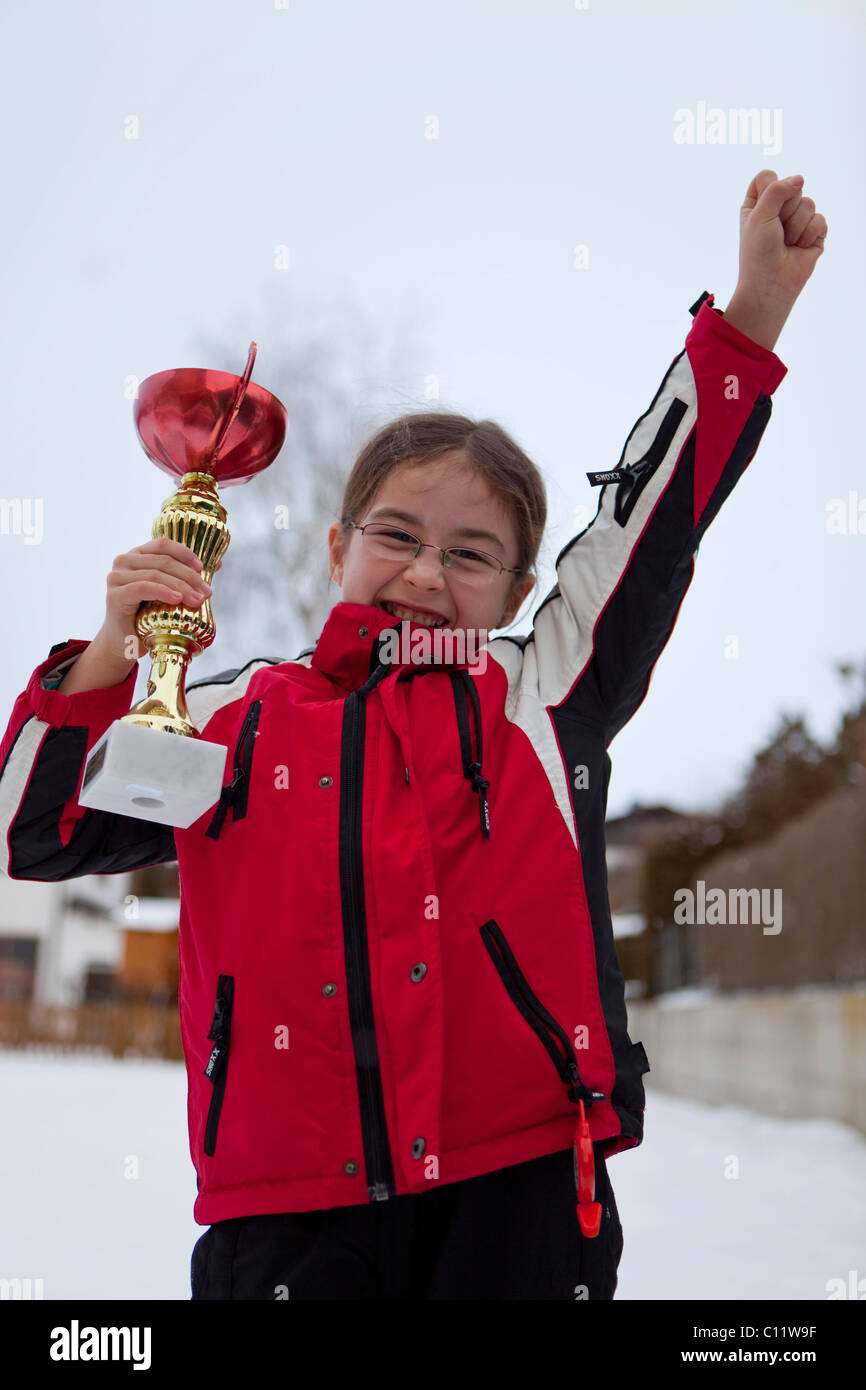 Girl, 9, rejoicing with a trophy at an awards ceremony Stock Photo