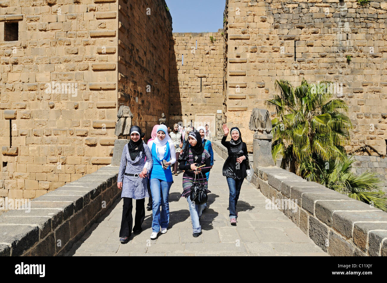Young women wearing headscarves at the entrance, Roman theater in Bosra, Syria, Asia Stock Photo