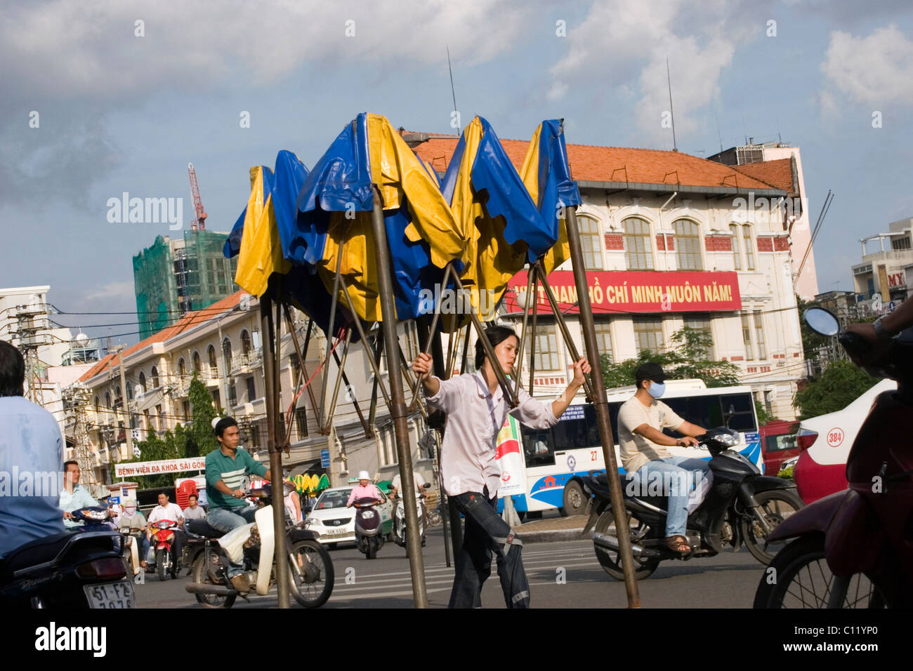 A woman is carrying a portable tent to a nearby night market on a busy street with heavy traffic in Saigon (Ho Chi Minh City) Vi Stock Photo