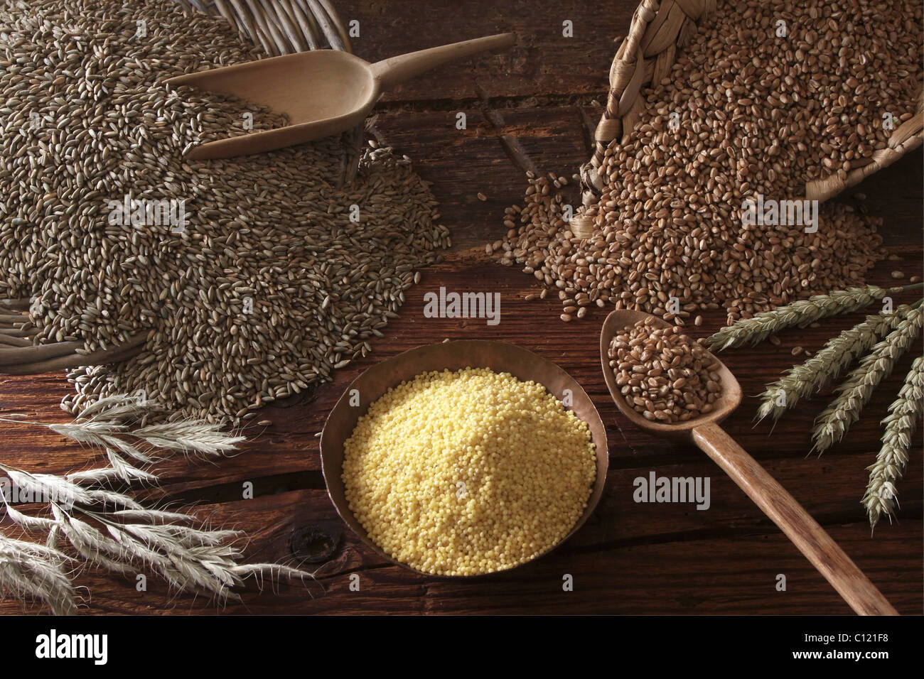 Different types of grain, Rye (Secale cereale), Wheat (Triticum) and Millet (Panicum miliaceum) on a wooden surface Stock Photo