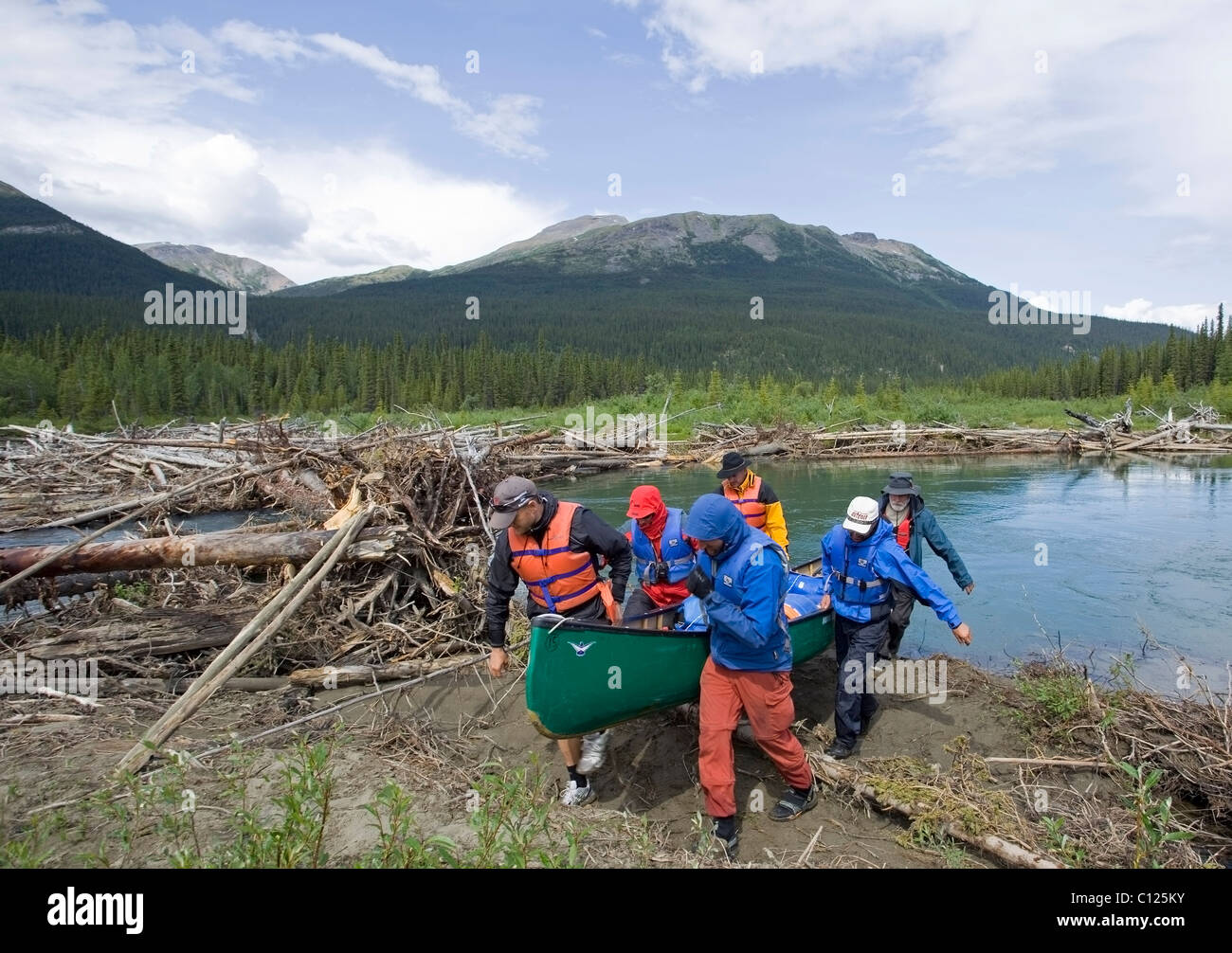 Men portaging, carrying a canoe over land, bypassing obstacle, log jam