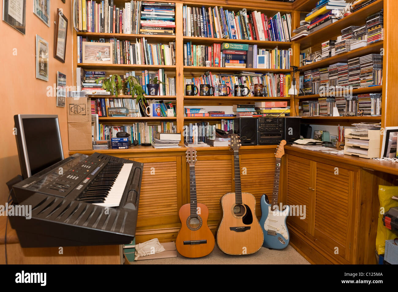 Study and music room with electric piano guitars and bookshelves in UK