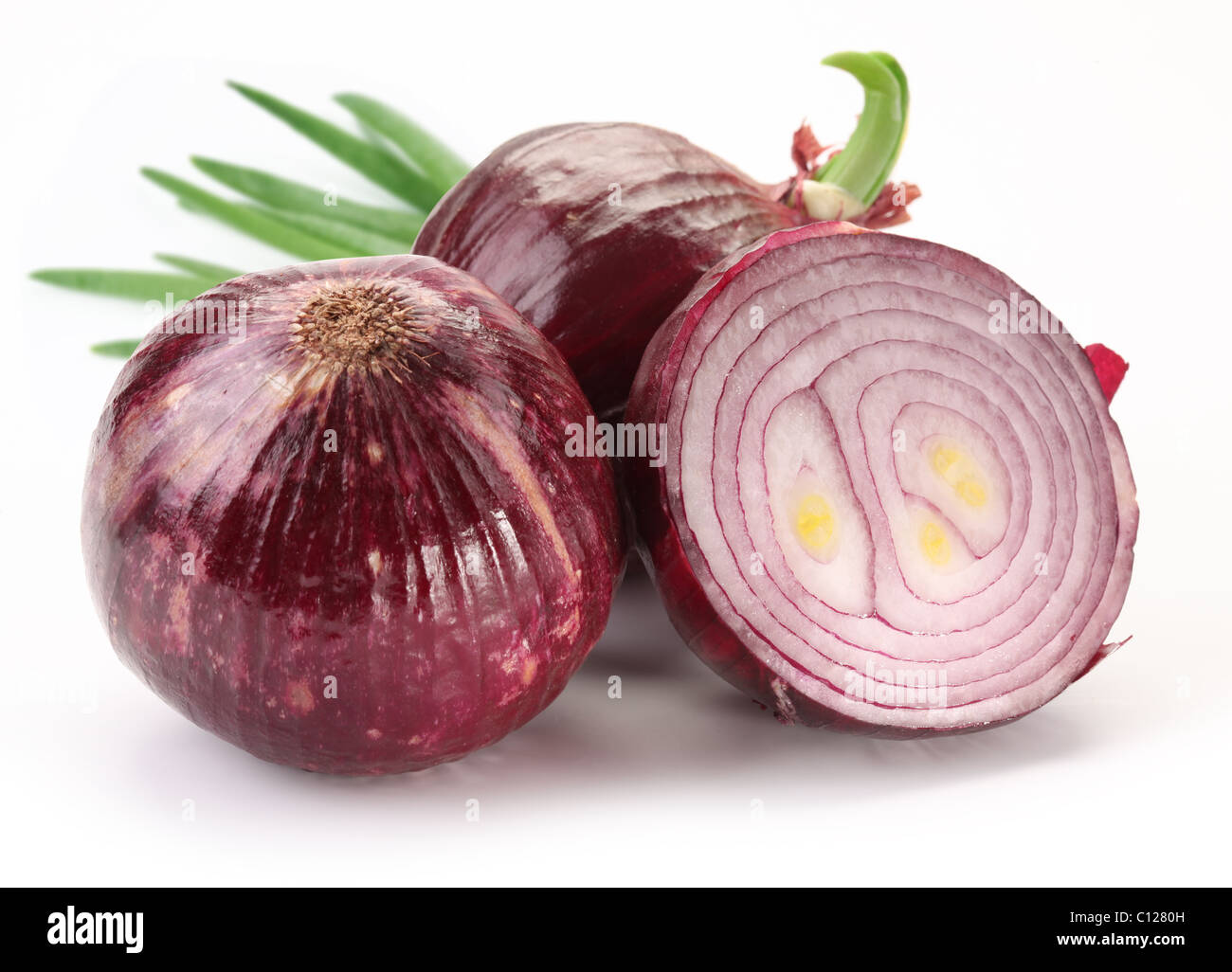 Bulbs of red onion with green leaves on a white background Stock Photo