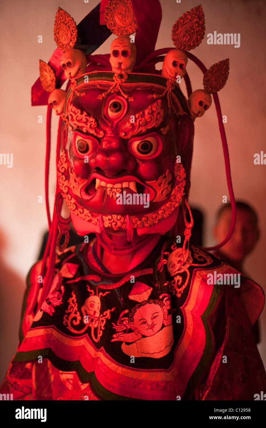 Buddhist monk dressed in ritual dance costume representing a god or demon prepares to dance at a religious festival Stock Photo