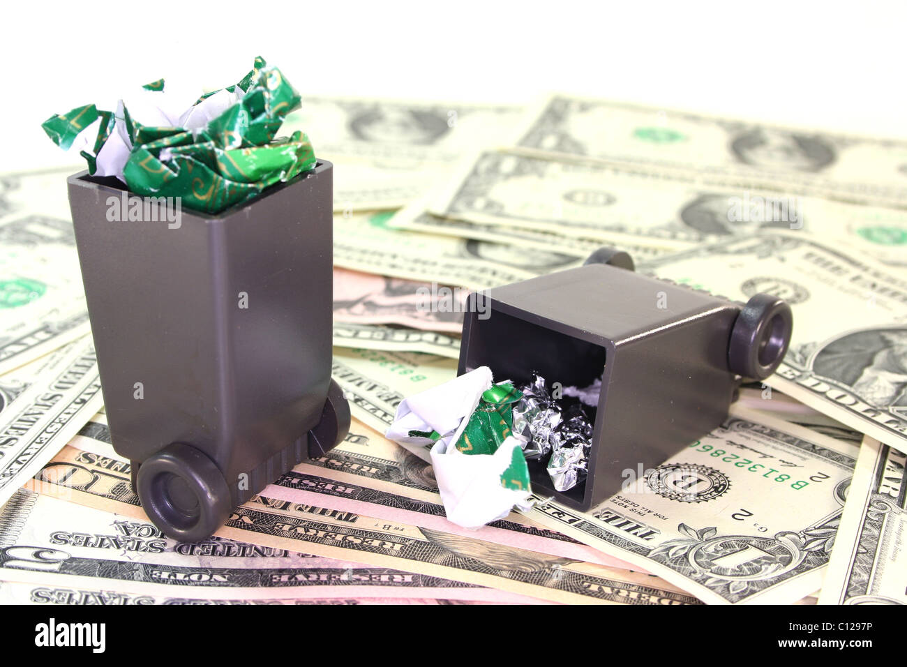 full garbage cans with dollar bills before a white background Stock