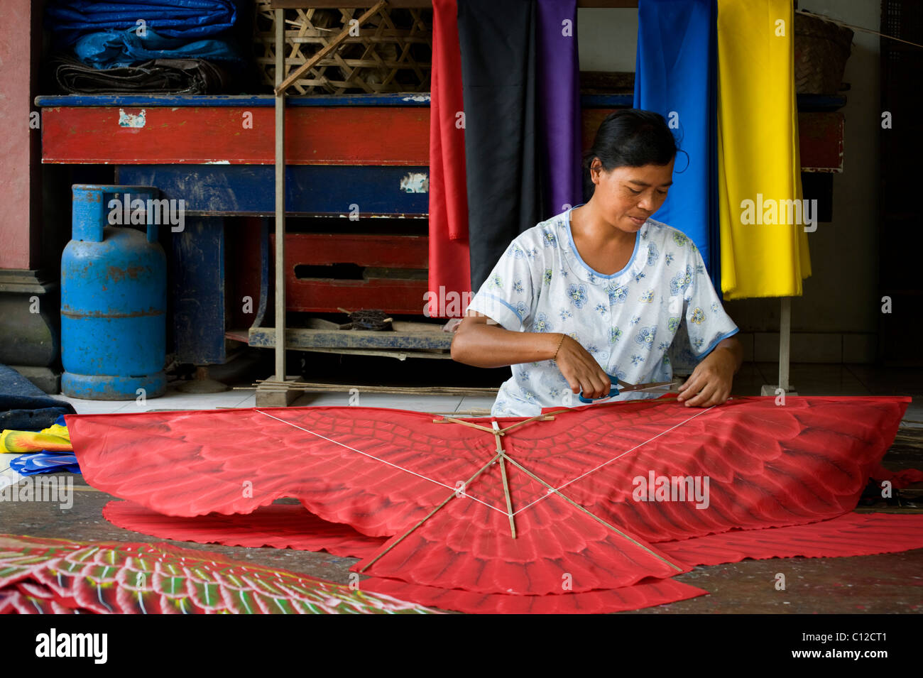 An artist and kite maker in the village of Sideman, Bali, puts the ...