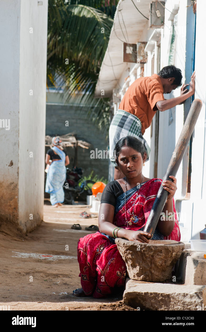 Indian woman using stone / wood mortar and pestle, pounding ingredients to make chutney. Andhra Pradesh, India Stock Photo