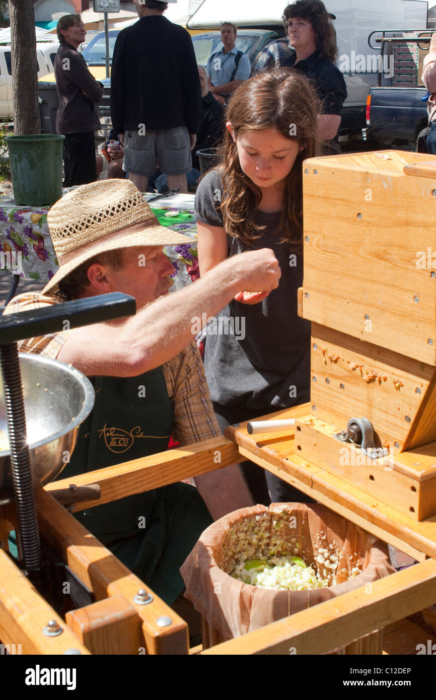 At Sebastopol farmer's market, volunteer hands cup of freshly pressed apple juice to a young girl. Stock Photo