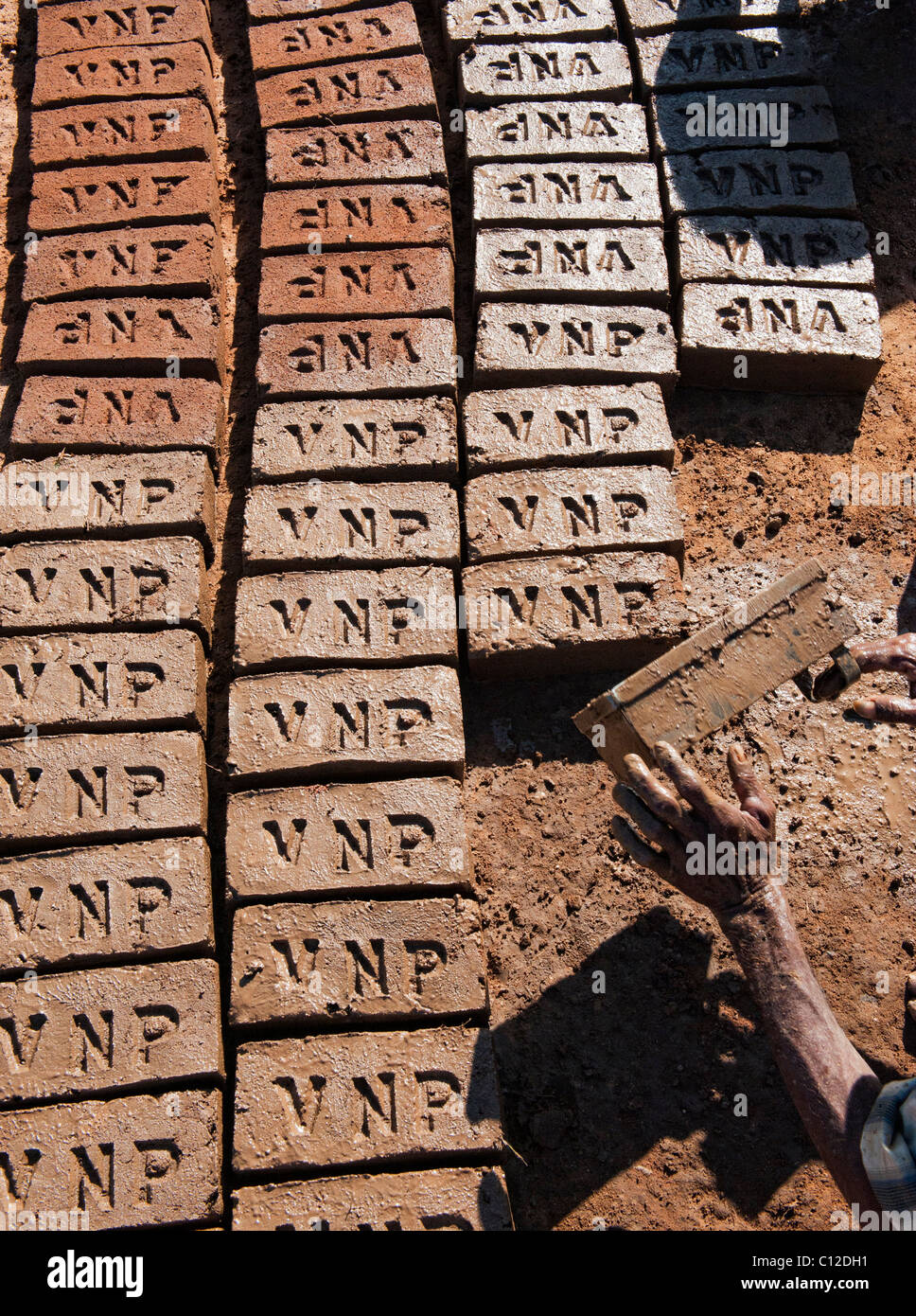 Indian men making house bricks by hand using a mould and wet clay / mud