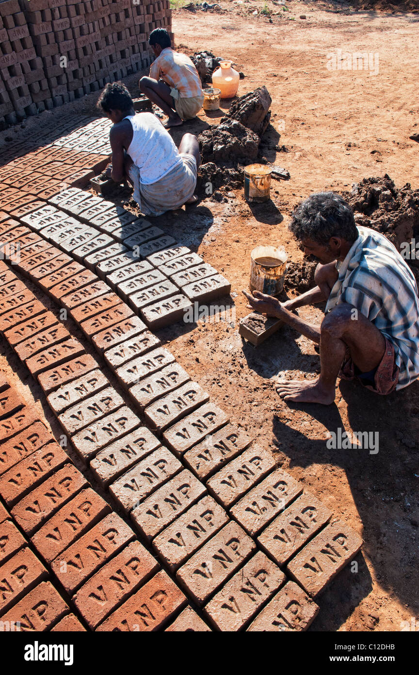Indian men making house bricks by hand using a mould and wet clay / mud