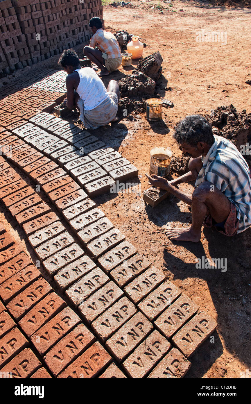 Indian men making house bricks by hand using a mould and wet clay / mud. Drying them in the sun before firing them hard. Andhra Pradesh, India Stock Photo