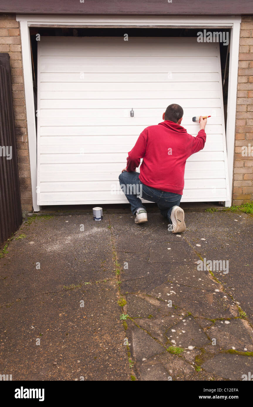 A MODEL RELEASED man doing DIY painting a garage door in the Uk Stock