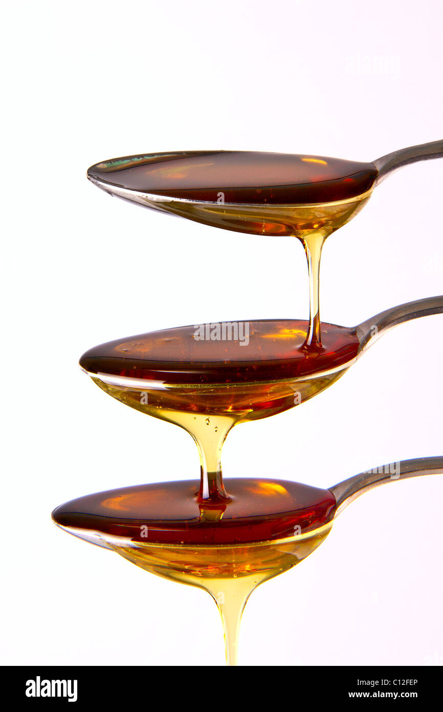 Syrup cascading down the spoons Stock Photo