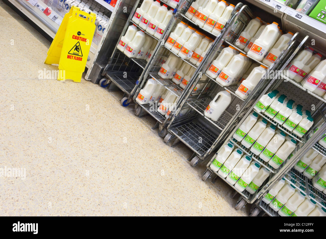 Crates of milk with wet floor sign where milk has been spilt in Sainsbury's supermarket in the Uk Stock Photo
