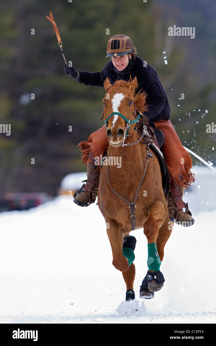 Horse and rider running in the snow while towing a skier during a ski