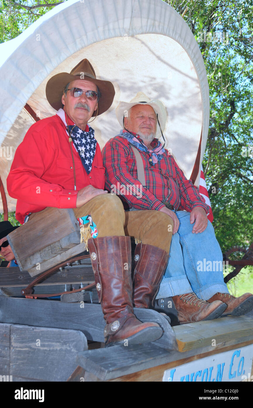 Two old west cowboys ride in a covered wagon at the 4th of July parade ...