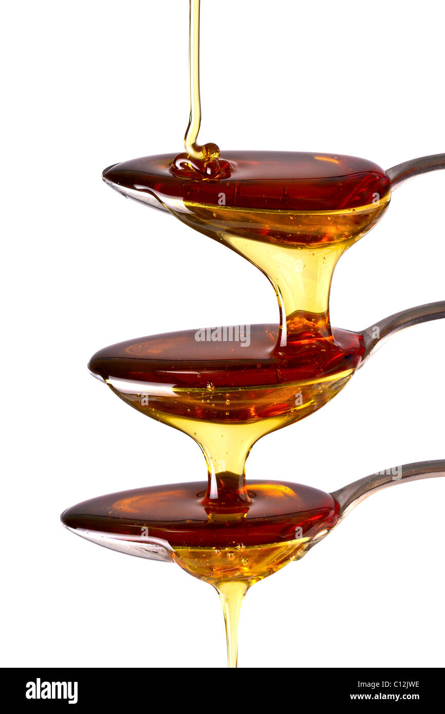 Syrup cascading down the spoons. Isolated on white background Stock Photo