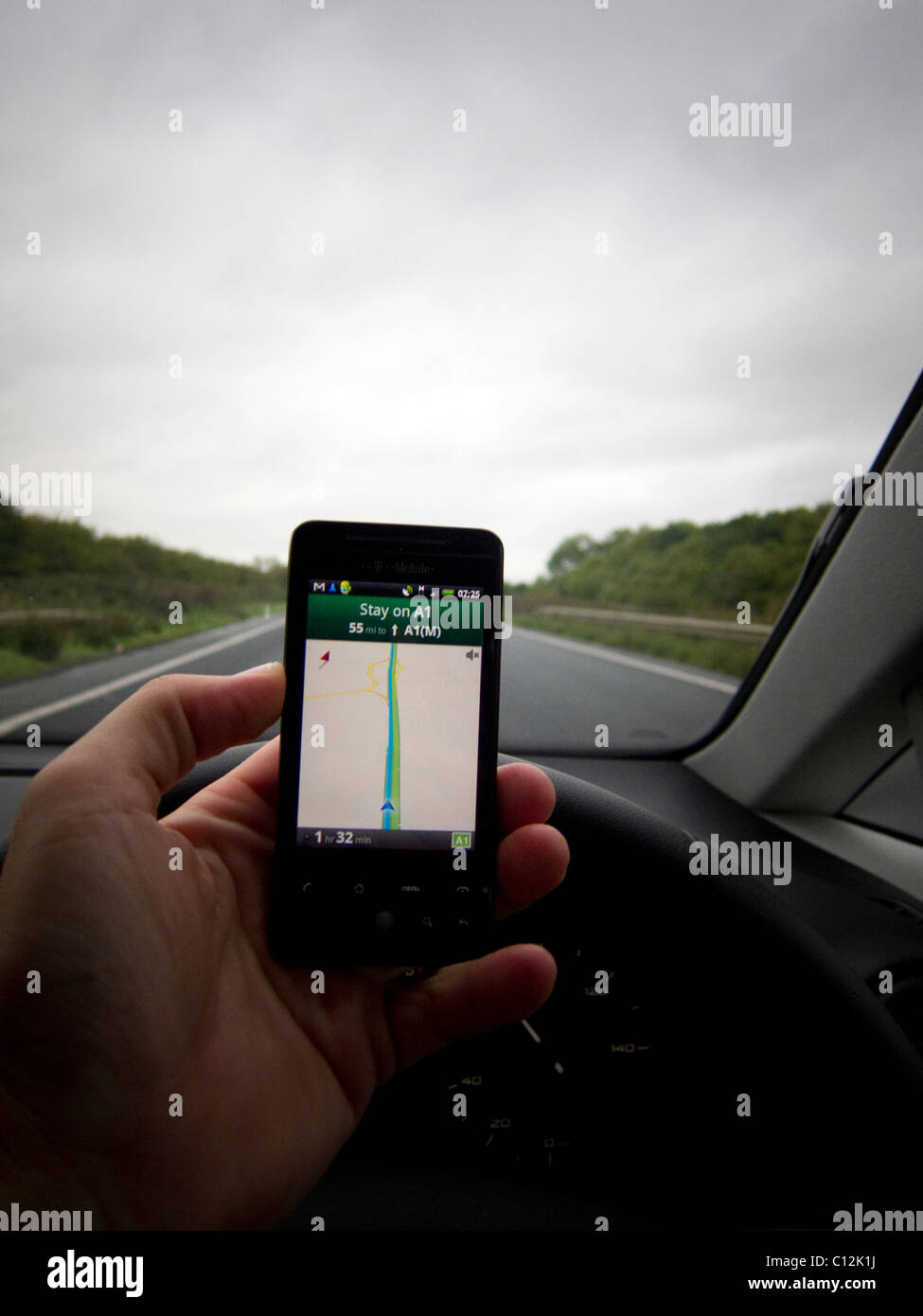 A Car driver driving whilst using a mobile device / mobile phone / smart phone. Driver using Google maps / navigation Stock Photo