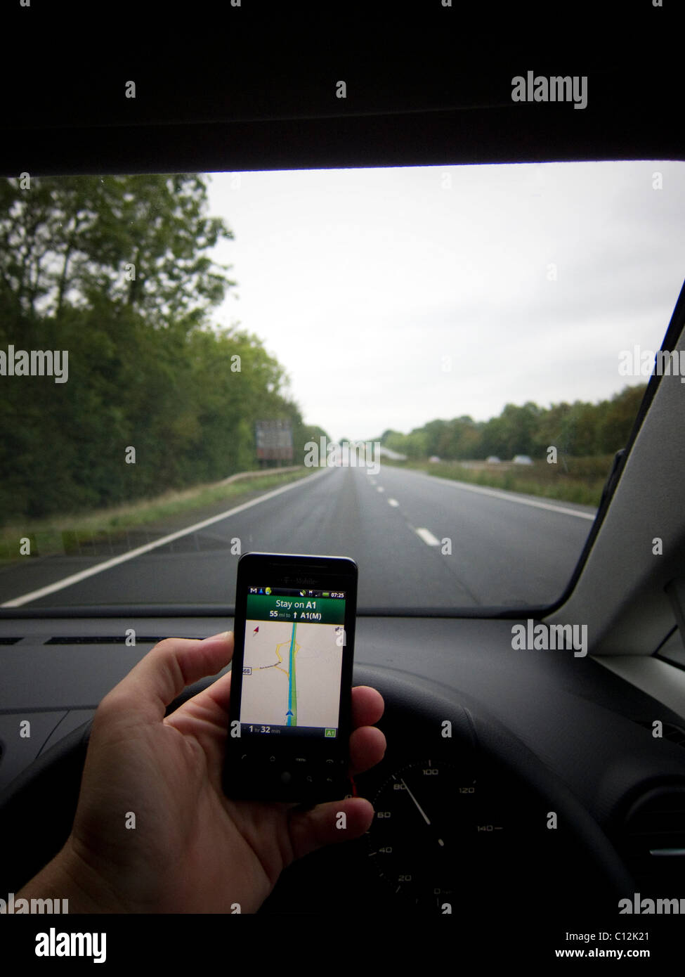 A Car driver driving whilst using a mobile device / mobile phone / smart phone. Driver using Google maps / navigation Stock Photo