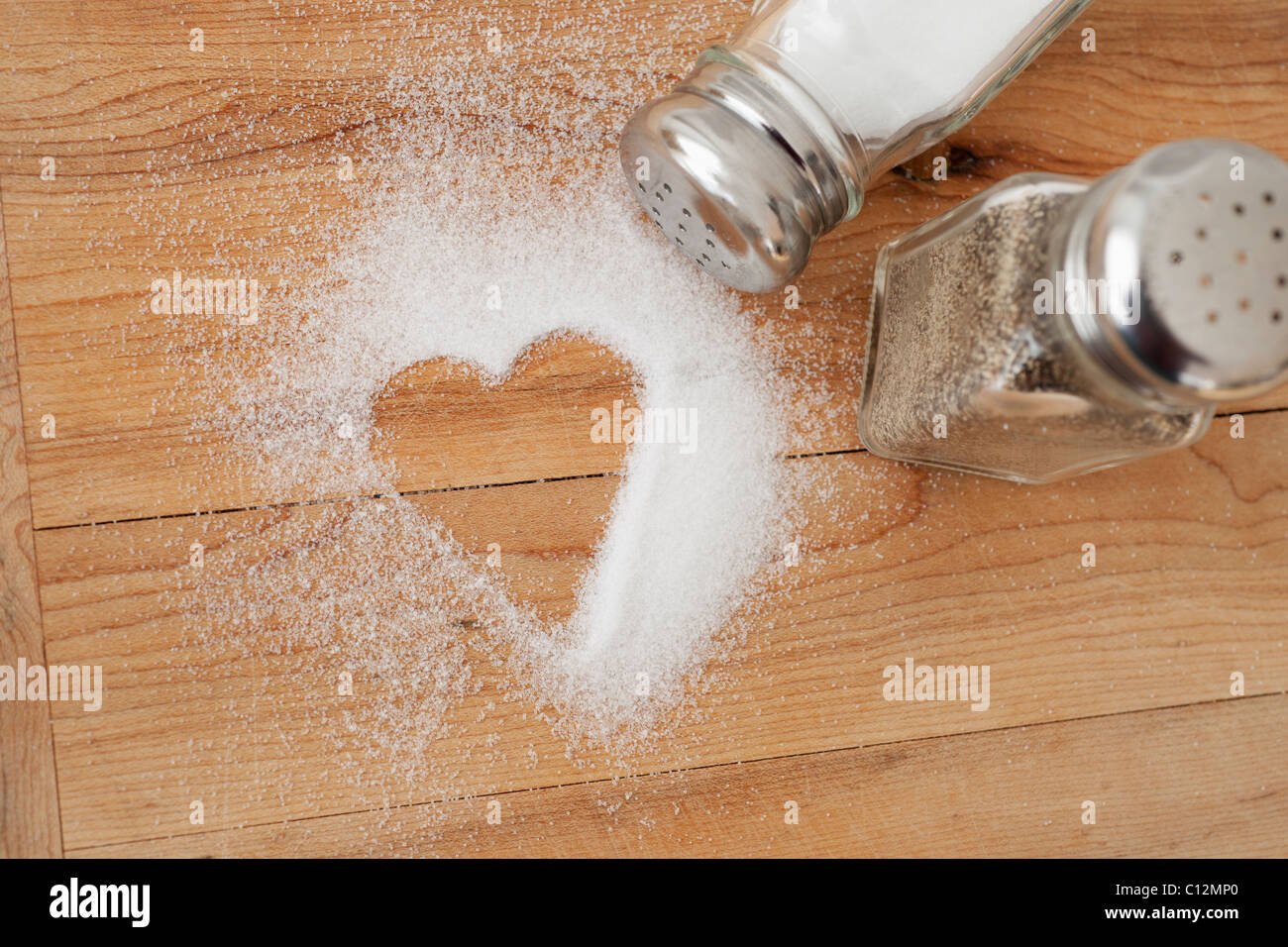 Heart shaped spilt salt on table Stock Photo