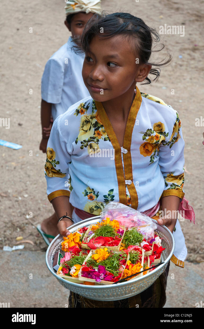 Young girl with temple offerings at a festival in Padang bai in Bali Stock Photo