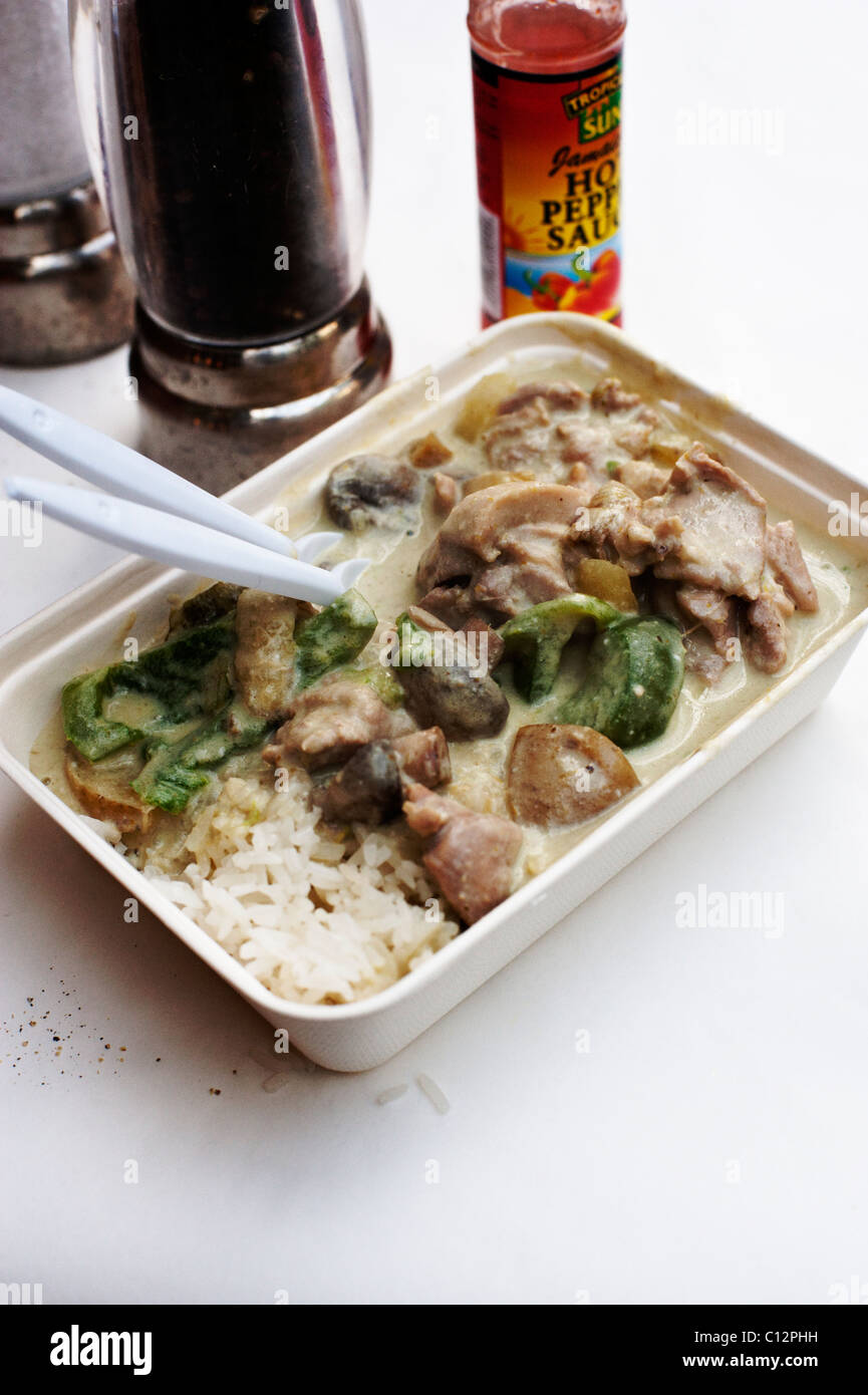 Thai curry served in a box with rice and chilli sauce behind at the Borough Market, London. Stock Photo