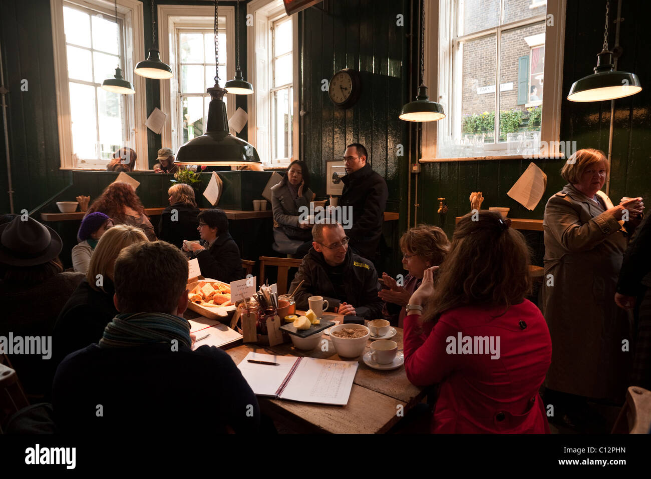 Coffee drinkers gathered around the central table at Monmouth Coffee shop at the Burough Market, London. Stock Photo