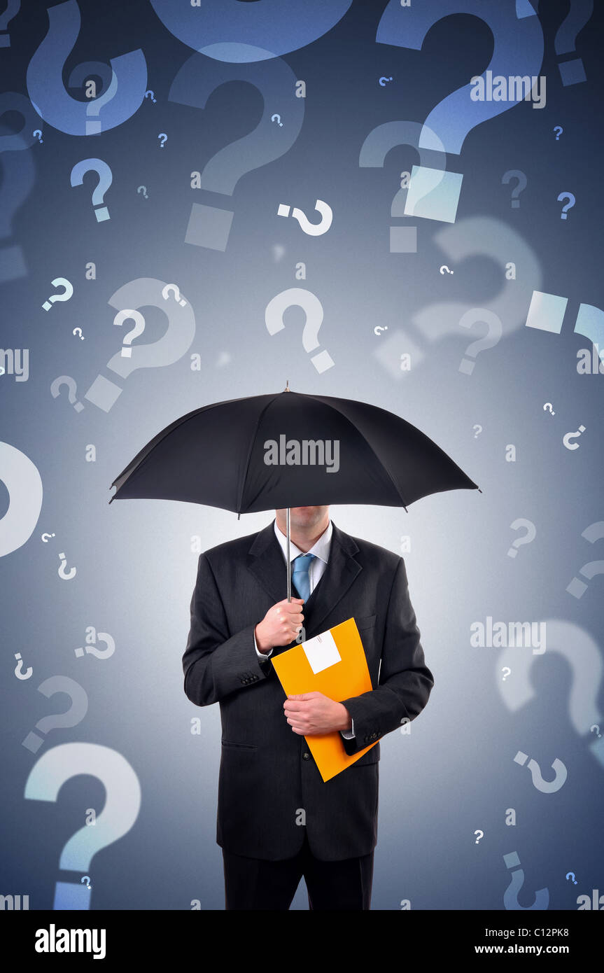 Businessman is holding an umbrella, question marks falling from the sky. Stock Photo